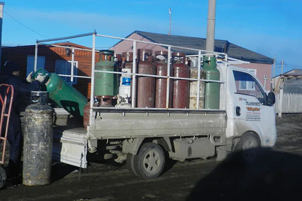 El fletero baja de su vehículo las garrafas de gas.