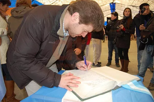 Gustavo Melella firma el libro de invitados en la Carpa de la Dignidad.