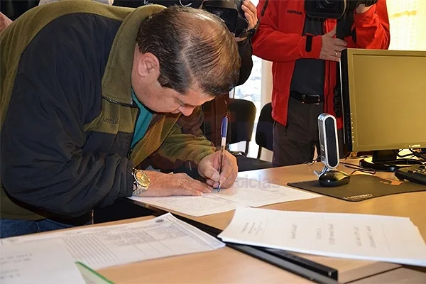 Uno de los beneficiarios rubrica la documentación de su terreno.