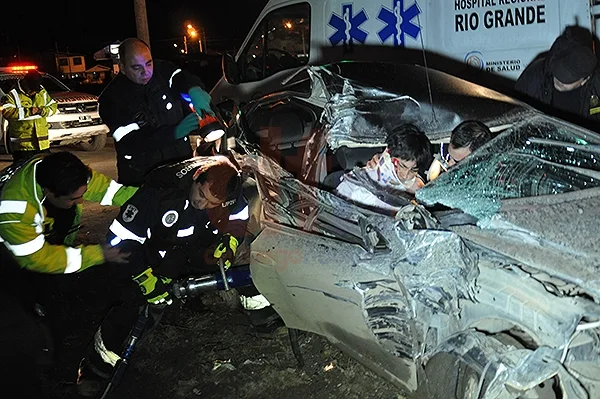 Bomberos y policías intentan rescatar al joven aprisionado dentro del automóvil.