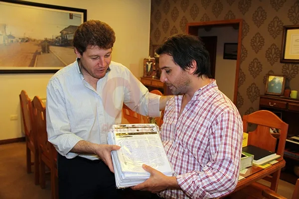 Mellela entrega a Juan Recce las planillas firmadas por los vecinos.